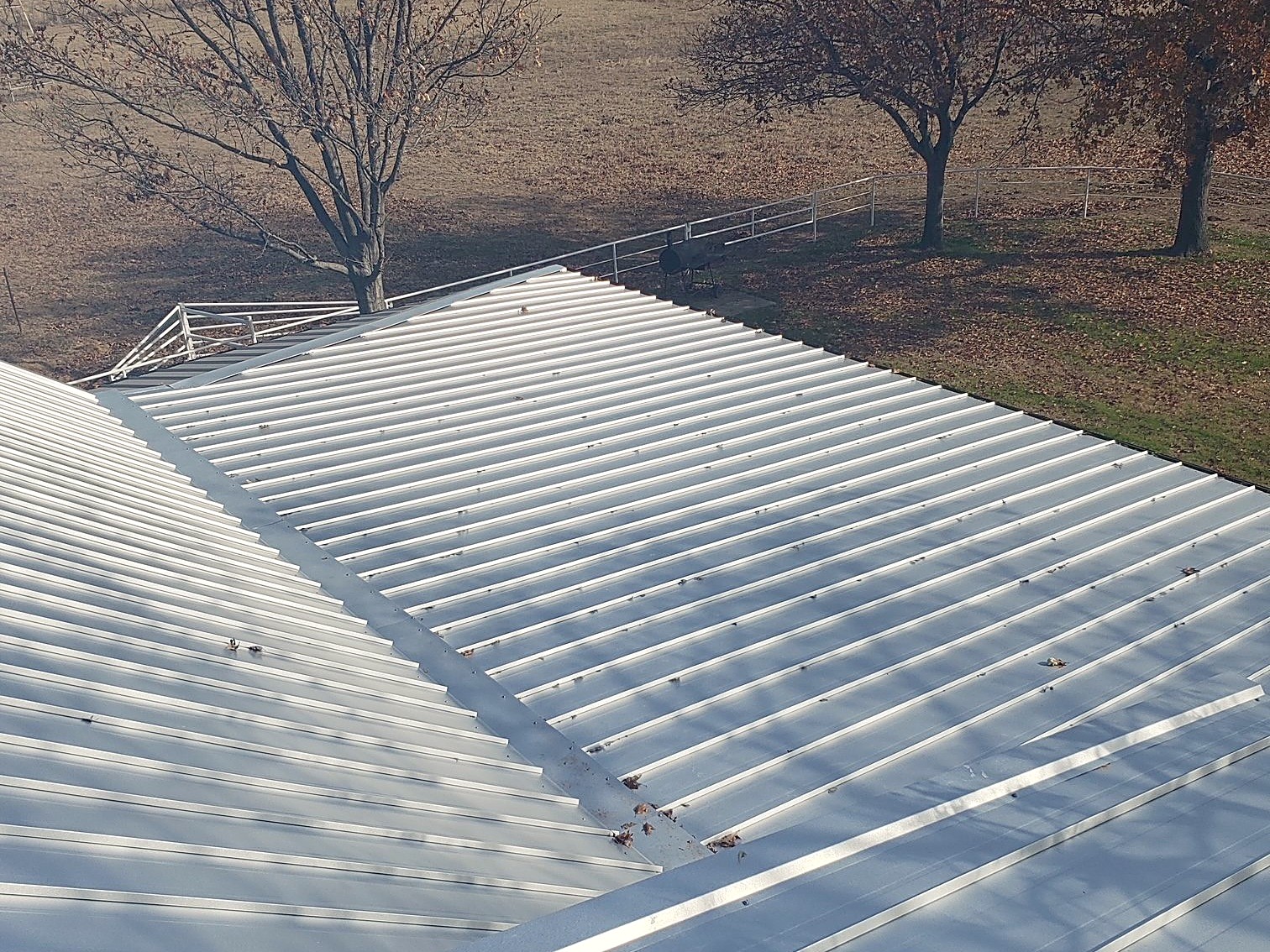 Metal roof panels running down to the eave of an outbuilding on open North Texas pasture