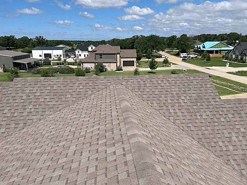 A newly shingled hip roof looking out over a rural North Texas street